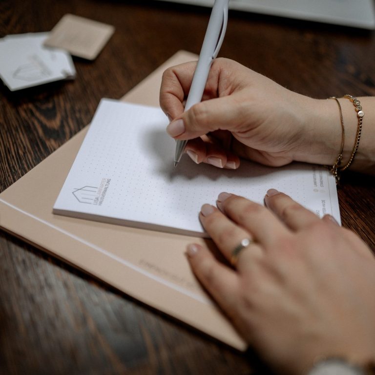 Zu sehen sind zwei Hände mit Kugelschreiber in der Hand, welche auf den Block der Lisa Hausverwaltung schreiben. 